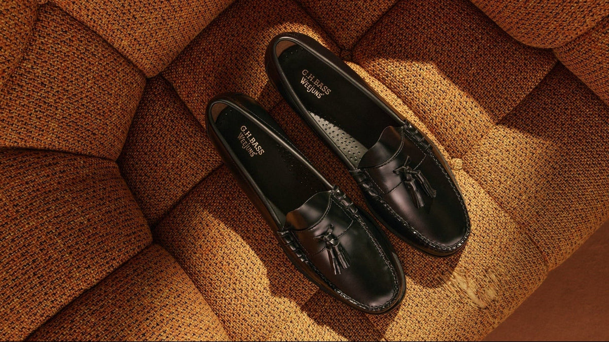 A pair of black tassel loafers on an orange couch