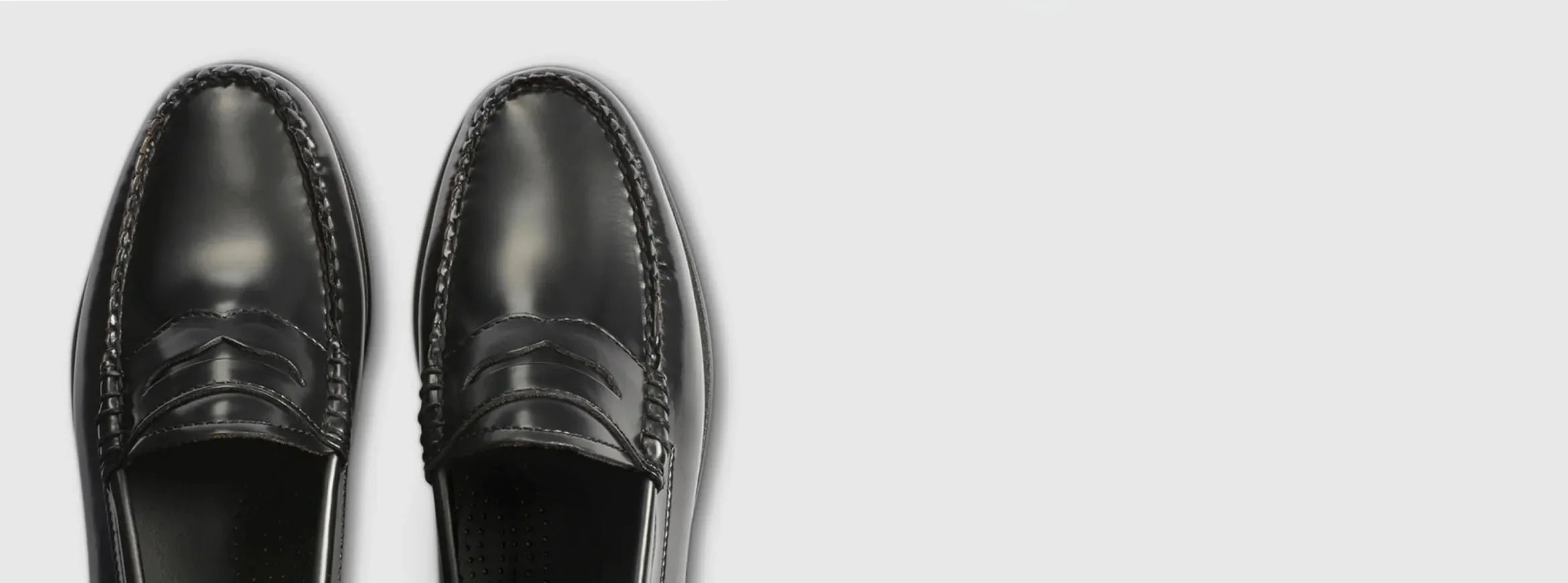 A pair of black loafers displayed against a light grey background
