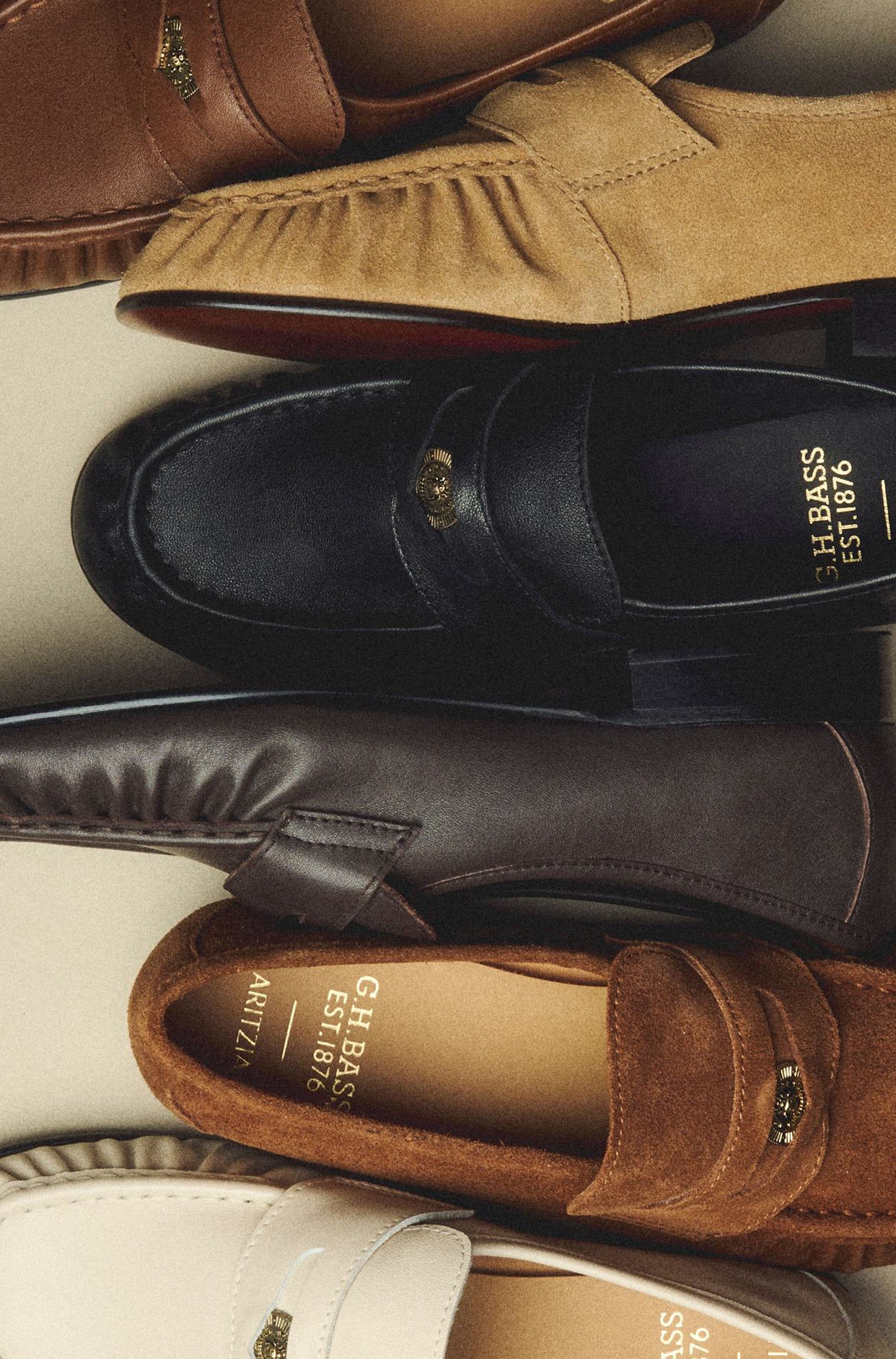 Brown, black, and beige suede and leather loafers displayed against a pale beige background