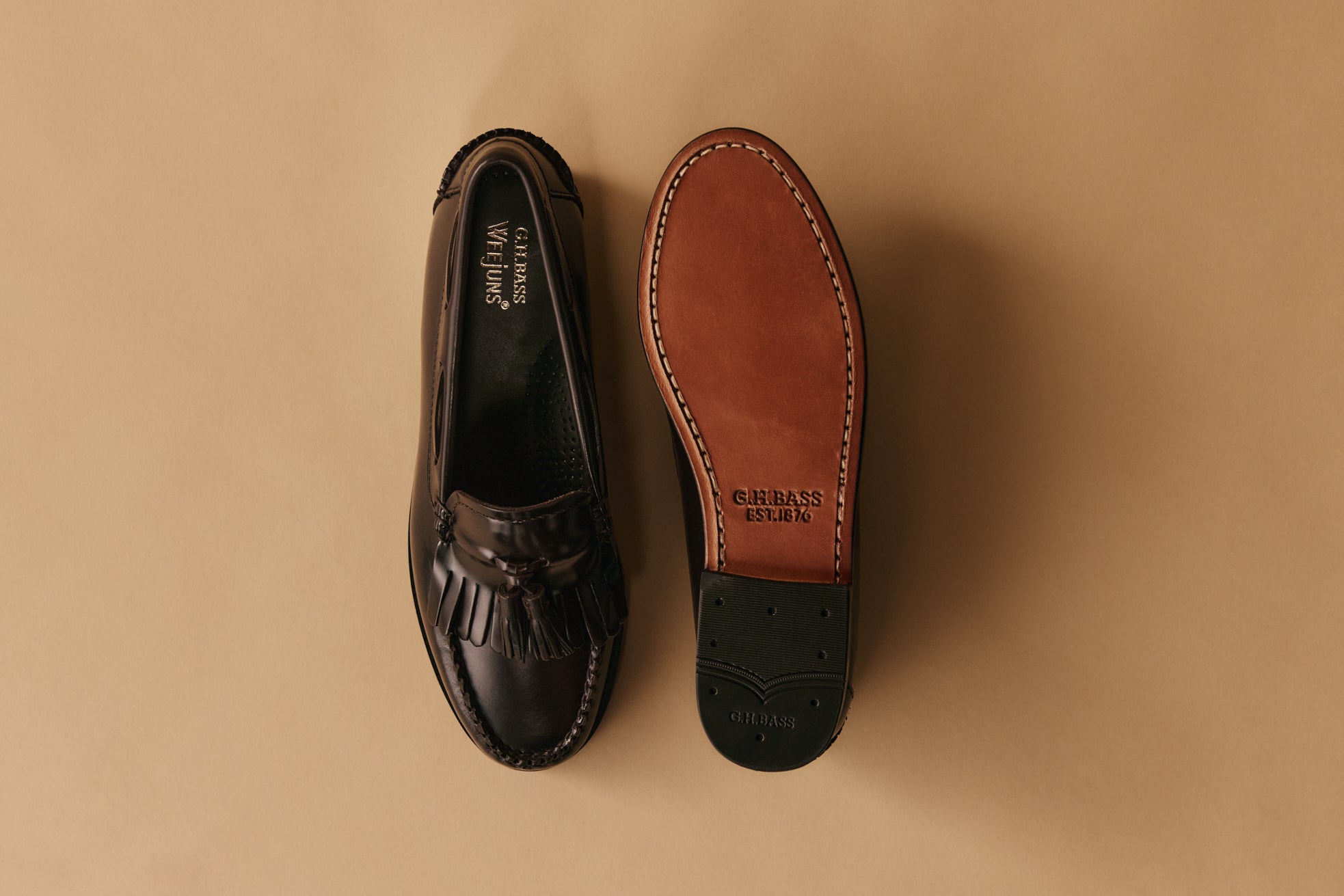 Black, white, and brown pairs of men's and women's loafers displayed against a pale green background