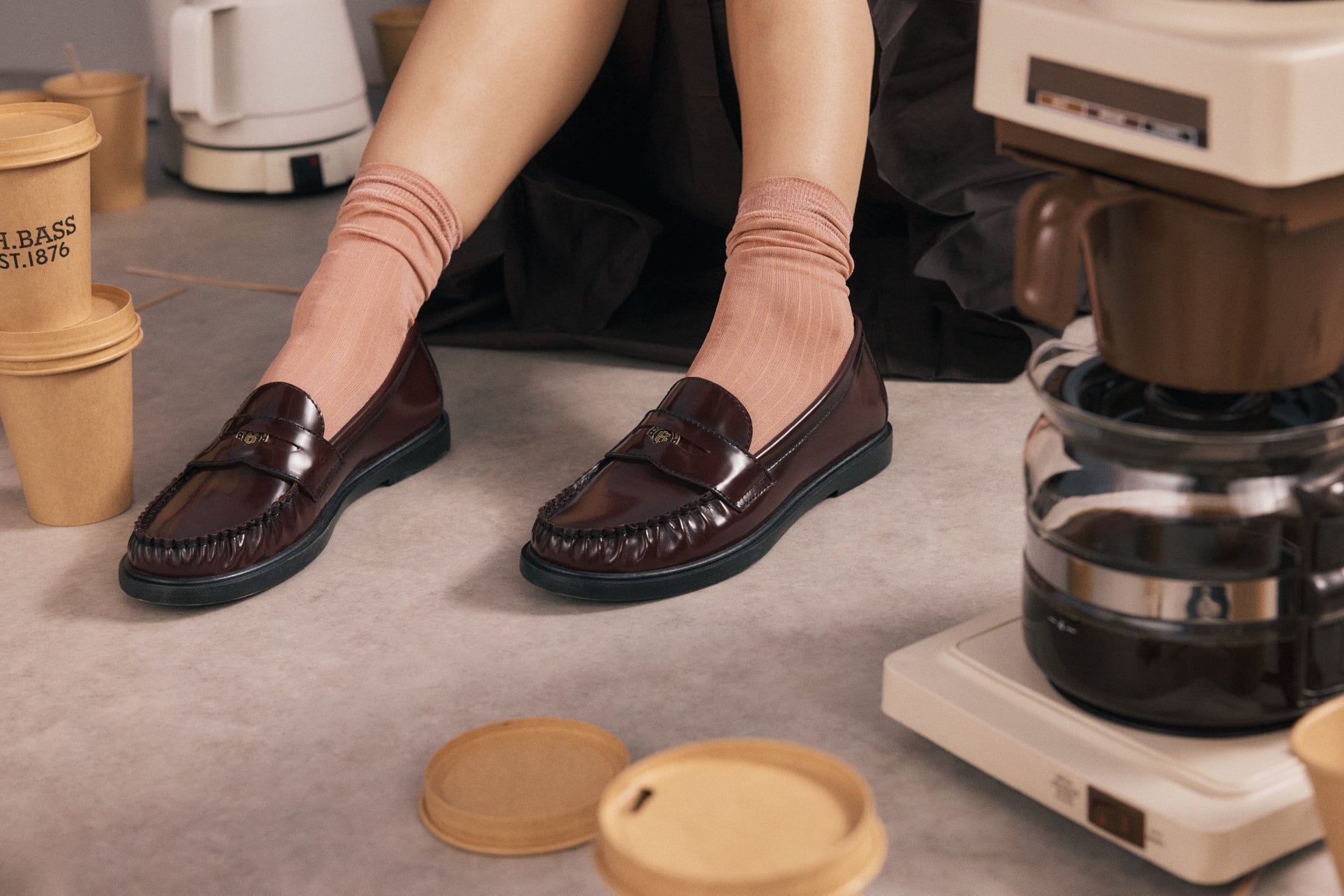 A close-up shot of a woman sitting on the floor wearing brown loafers
