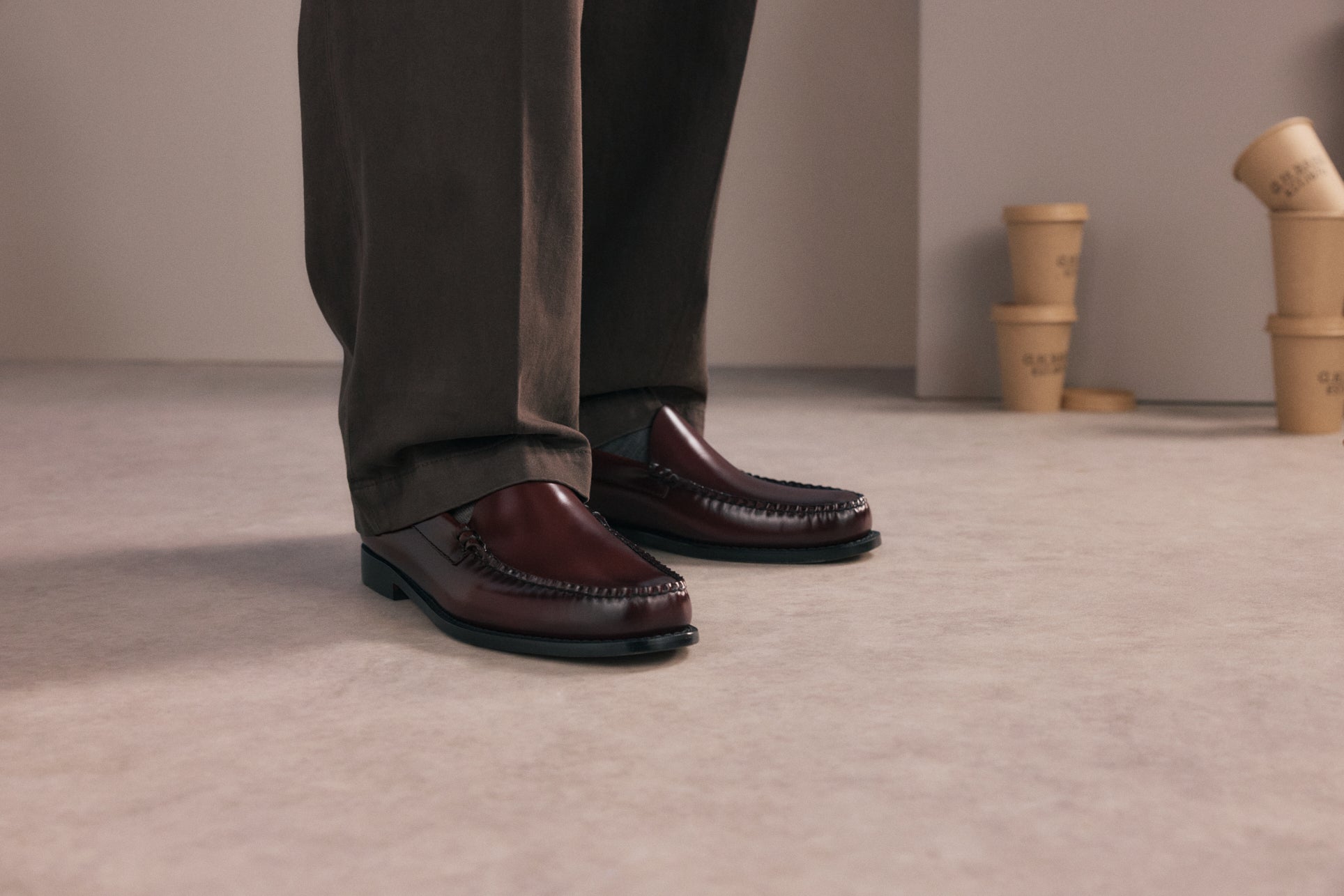 Black, white, and brown pairs of men's and women's loafers displayed against a pale green background